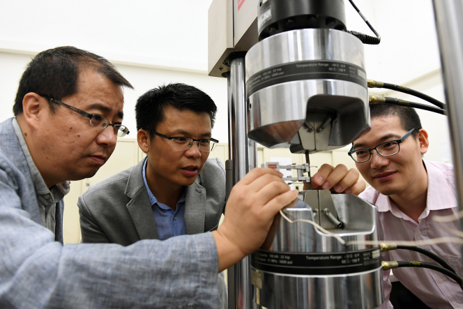 The research team uses a tensile machine to test the yield strength and elongation of steel. (From right): Dr He Binbin, Dr Huang Mingxin Dr Luo Haiwen.